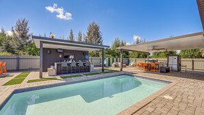 Ein Garten mit Schwimmbad, Sitzgelegenheit im Freien und Grillplatz.