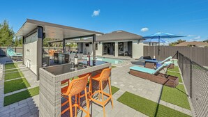 Eine moderne Außenpatio mit Pool, Bar und Sitzgelegenheiten.