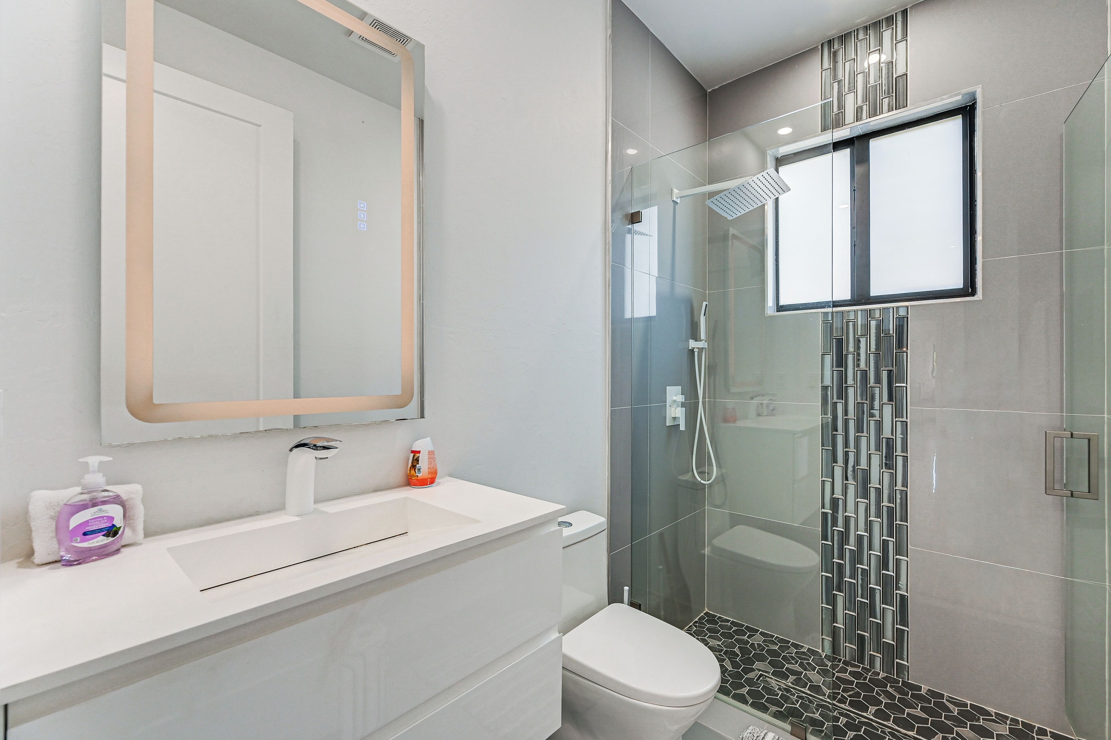 Une salle de bain moderne avec une douche à parois de verre, un lavabo blanc et des toilettes.