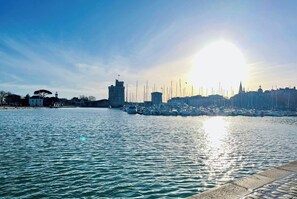 Ein Yachthafen am Wasser mit Booten, einem Turm und Gebäuden im Hintergrund.