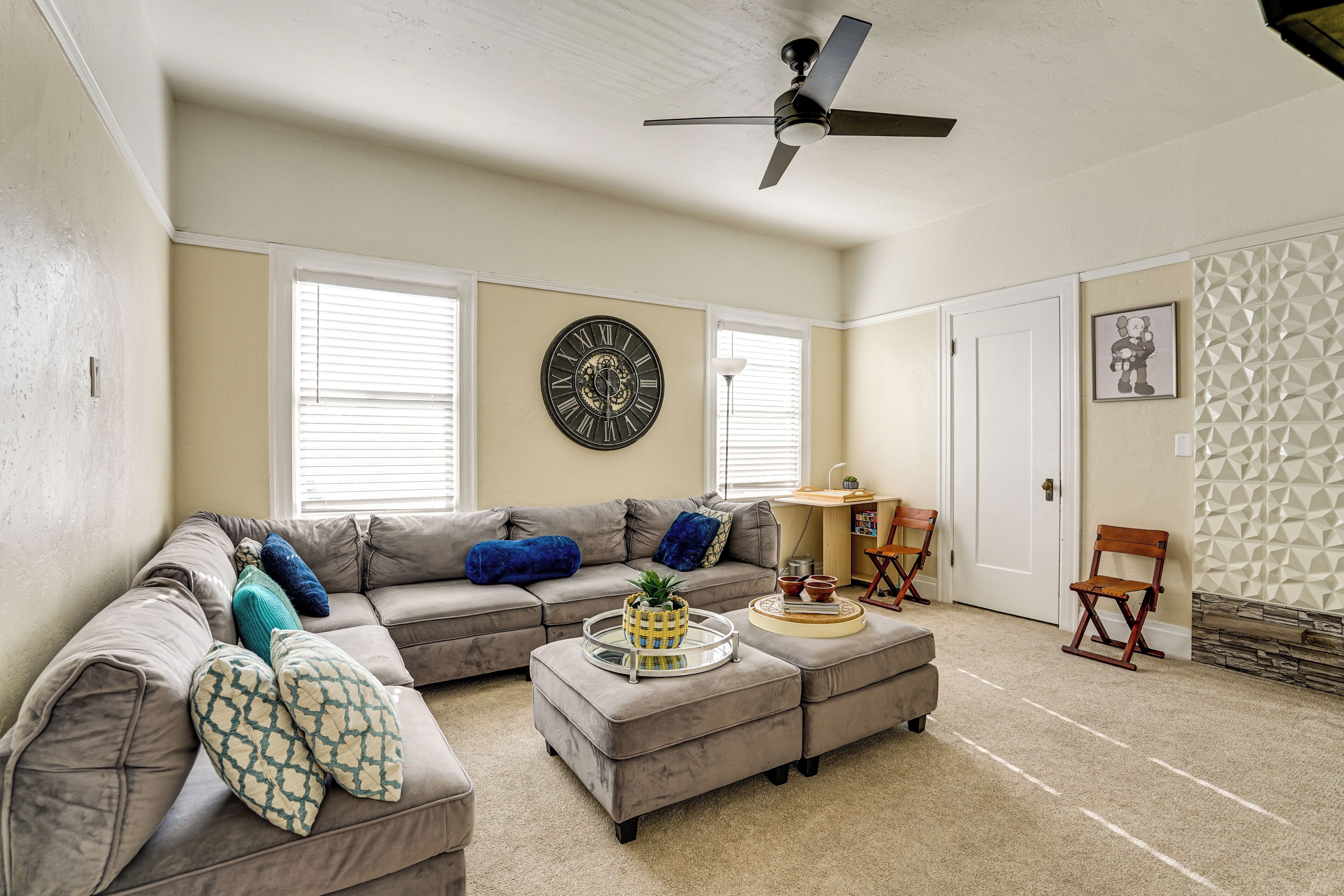 A living room with a sectional sofa, ottoman, and a ceiling fan.