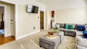 A spacious living room with a grey sofa set, a coffee table, and a flat-screen TV mounted on the wall. - Pet-friendly Condo < 2 Mi to Alameda Beach! (Alameda)