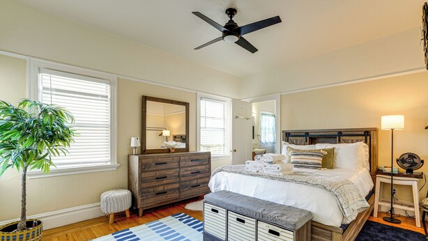 A bedroom with a bed, bedside tables, a ceiling fan, a potted plant, and a large window. - Pet-friendly Condo < 2 Mi to Alameda Beach! (Alameda)