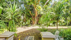 A garden with a statue of a woman, a paved walkway, and various tropical plants. - 3 Mi to 5th Ave South: Quiet Getaway w/ Garden (Naples)