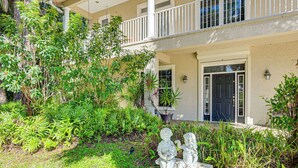 A two-story building with a balcony, surrounded by lush greenery and a garden. - 3 Mi to 5th Ave South: Quiet Getaway w/ Garden (Naples)