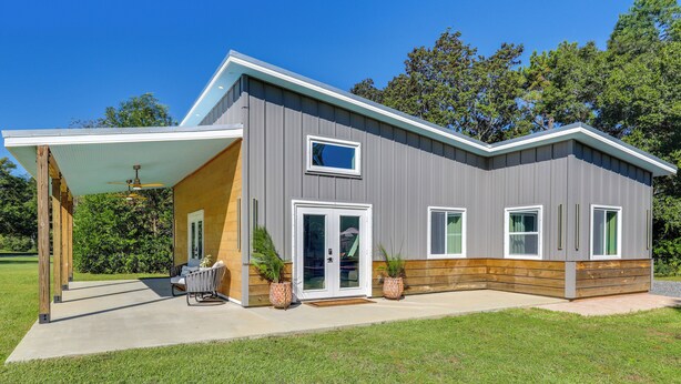 A modern house with a covered patio, a sliding glass door, and a small outdoor seating area. - Fish, Boat & Unwind: Gem 6 Mi to Gulf Shores Beach (Gulf Shores)