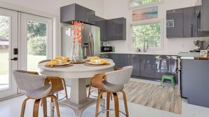 A modern kitchen with a round dining table, grey chairs, and a green stool. - Fish, Boat & Unwind: Gem 6 Mi to Gulf Shores Beach (Gulf Shores)
