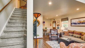 Un escalier menant à un espace de vie comprenant un canapé, des fauteuils et une table à manger.
