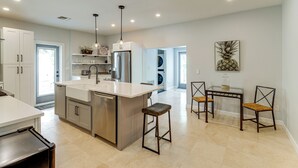 A modern kitchen with a central island, stainless steel appliances, and a dining area with a table and chairs. - Walk to Wabasso Beach: Home w/ Hot Tub & Bikes (Vero Beach)