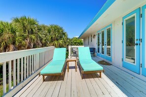 A wooden deck with two lounge chairs and a small table, overlooking a lush green landscape. - Walk to Wabasso Beach: Home w/ Hot Tub & Bikes (Vero Beach)