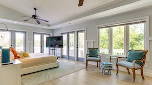 A spacious bedroom with a large bed, a ceiling fan, and a TV. There are two chairs and a small table. - Walk to Wabasso Beach: Home w/ Hot Tub & Bikes (Vero Beach)