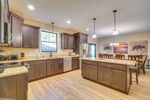 A modern kitchen with wooden cabinets, granite countertops, stainless steel appliances, and pendant lighting. - Walk to Dollywood! Cabin w/ Pool, Arcade, Gym (Pigeon Forge)