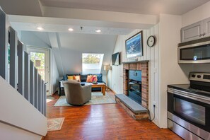 A modern kitchen with a built-in oven and microwave, a dining area with a table and chairs, and a cozy living room with a fireplace. - Steps to Ski Lifts! Mountain Green Resort Retreat (Killington)