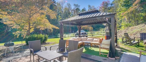 A covered outdoor seating area with wicker furniture and a barbecue grill.