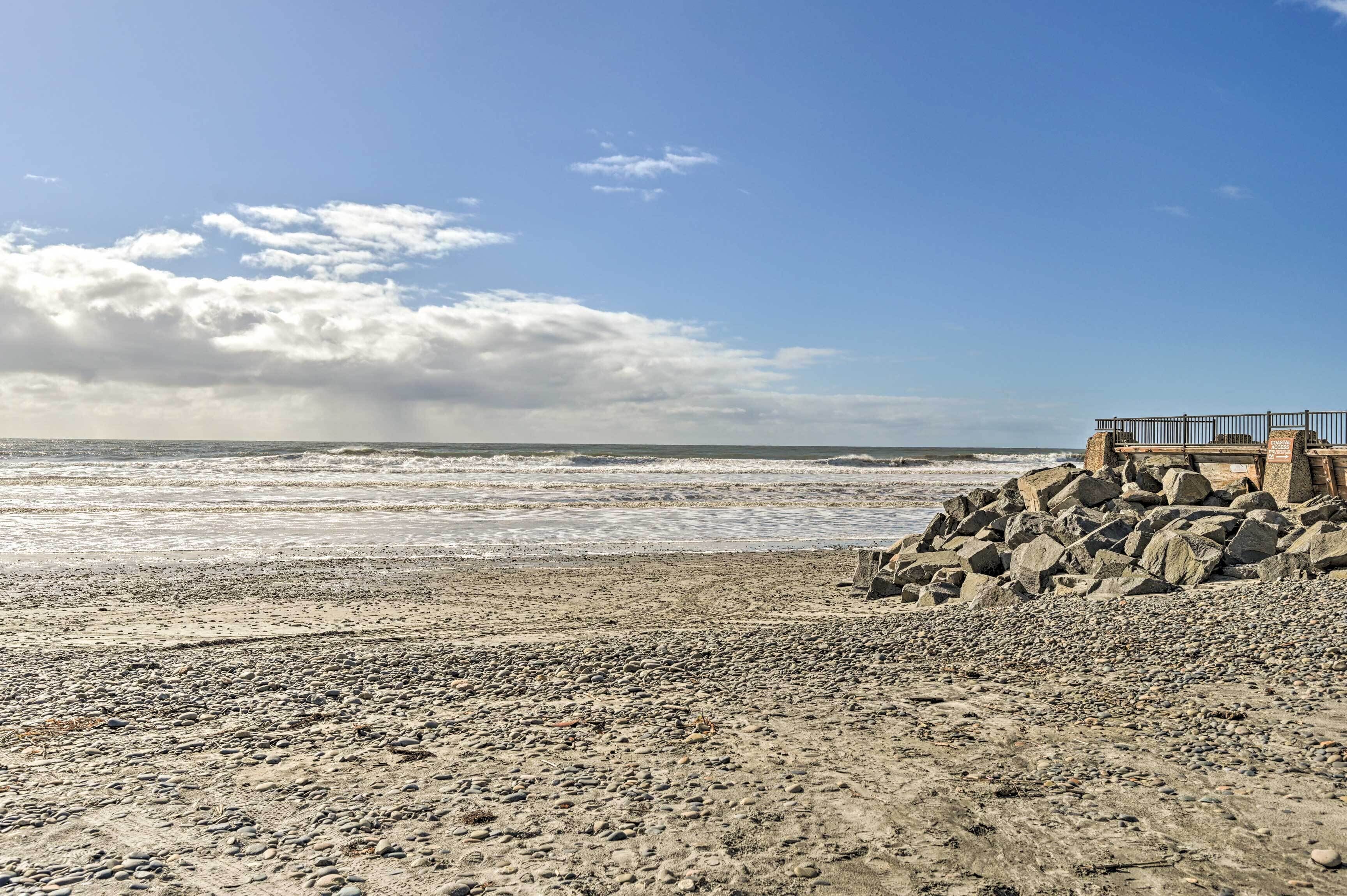 A beach with a rocky shoreline and a wooden structure on the right.