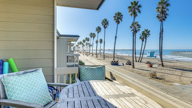 Eine Holzterrasse mit Blick auf einen Strand und Palmen.