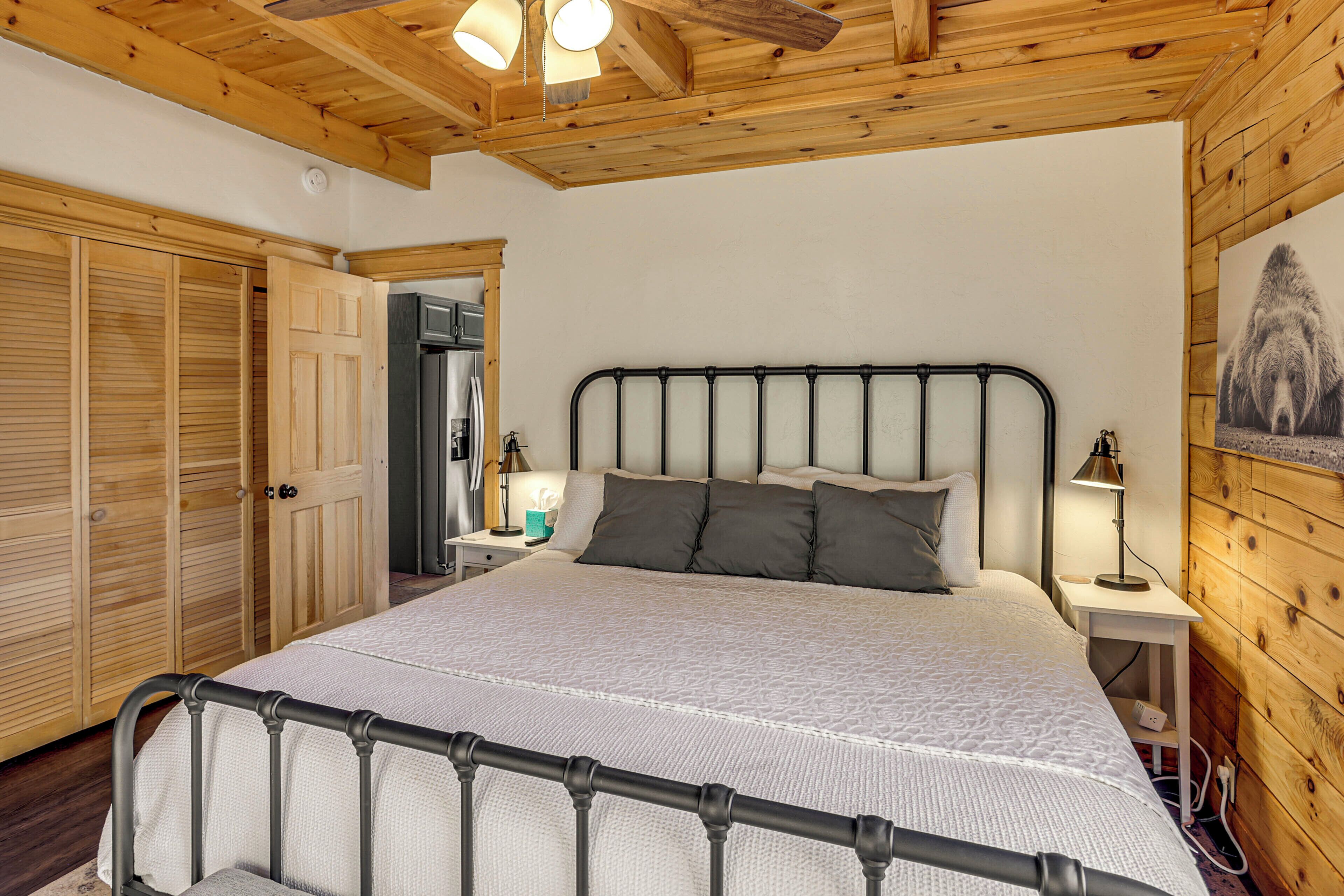 A bedroom with a large bed, wooden ceiling, and a wooden wall with a bear picture.