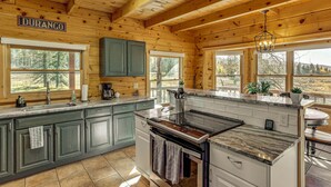 A wooden cabin kitchen with a large island, green cabinets, and a sign that reads "DURANGO". - Stunning San Juan Mtn Views: Cabin Near Skiing! (Durango)