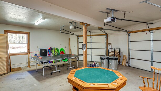 Eine geräumige Garage mit Tischtennisplatte, Holztisch und Stuhl.