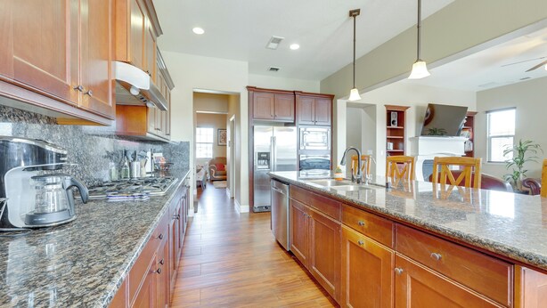 A kitchen with granite countertops, wooden cabinets, stainless steel appliances, and pendant lighting. - Outdoor Oasis w/ Fire Pit: Pet-friendly Fresno Gem (Fresno)