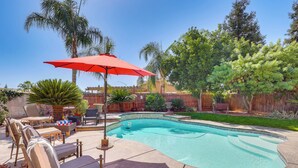 A backyard with a swimming pool, patio furniture, and a red umbrella. - Outdoor Oasis w/ Fire Pit: Pet-friendly Fresno Gem (Fresno)
