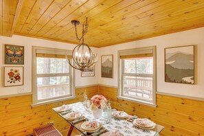 A dining area with a wooden ceiling, a chandelier, and a table set for four with floral arrangements. - 3 Mi to Snow Summit: Charming Home w/ Fenced Yard (Big Bear Lake)