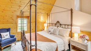 A wooden-paneled bedroom with a four-poster bed, a nightstand with a lamp, and a chair with a cushion. - 3 Mi to Snow Summit: Charming Home w/ Fenced Yard (Big Bear Lake)