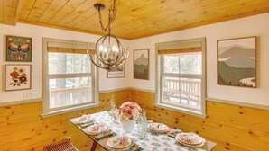 A dining area with wooden paneling, a chandelier, and artwork on the walls. - 3 Mi to Snow Summit: Charming Home w/ Fenced Yard (Big Bear Lake)
