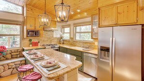 A kitchen with wooden cabinets, a granite countertop, stainless steel appliances, and a large island with seating. - 3 Mi to Snow Summit: Charming Home w/ Fenced Yard (Big Bear Lake)