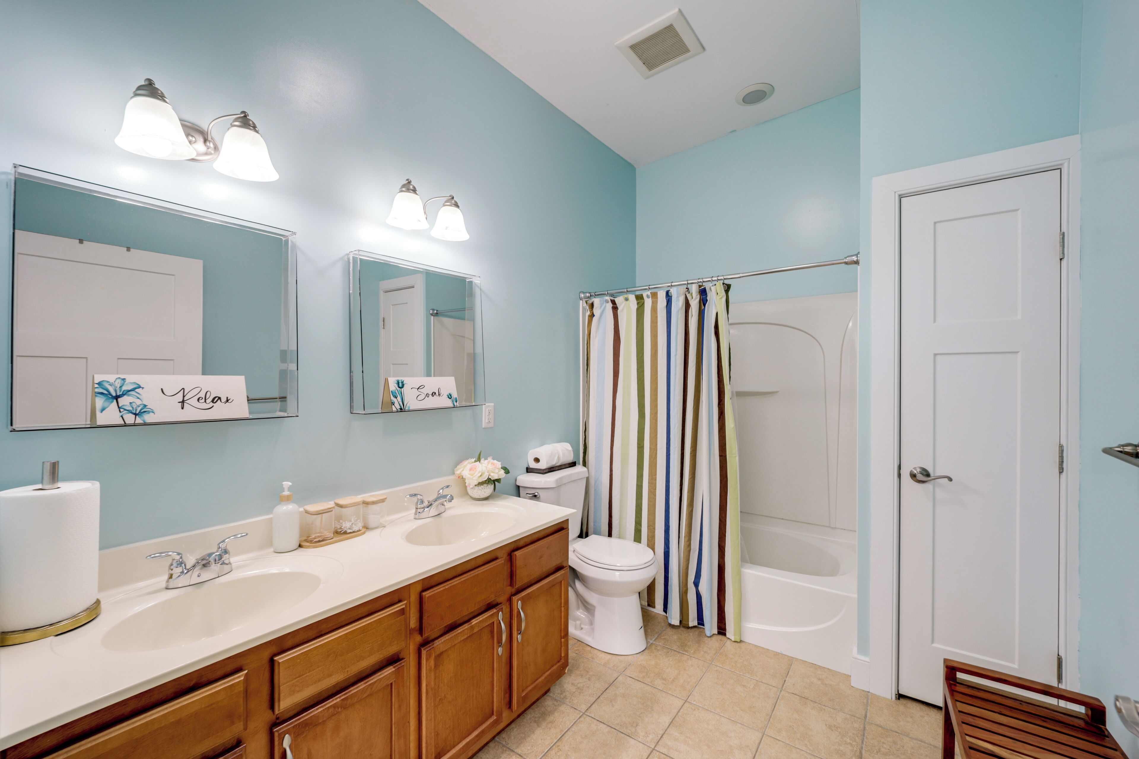 A bathroom with a double sink vanity, a toilet, a bathtub, and a shower curtain.