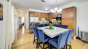 Una cucina moderna con mobili in legno, un piano di lavoro in marmo e sedie rivestite in blu.