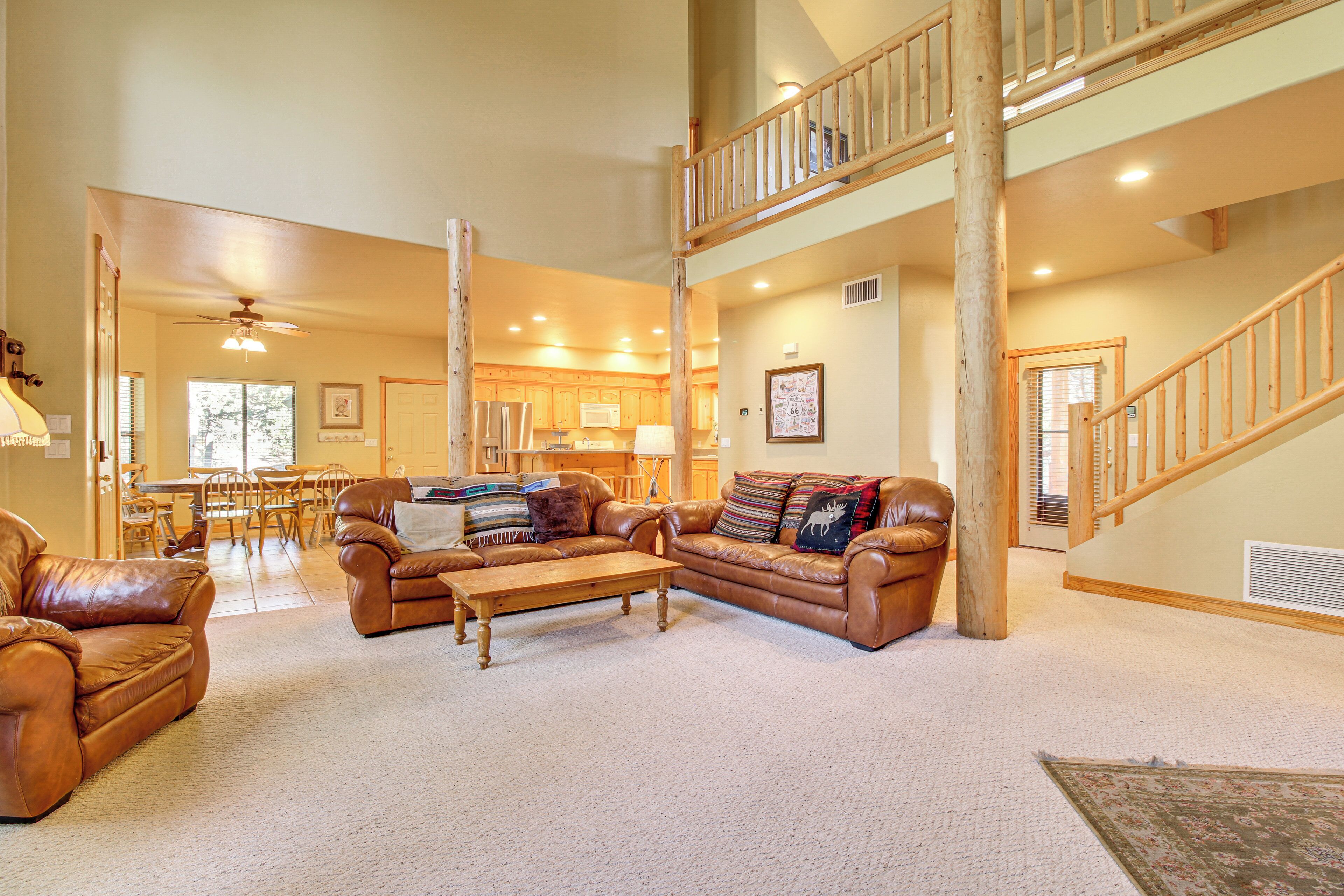 A spacious living room with leather sofas, a wooden coffee table, and a staircase leading to an upper level.
