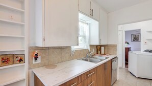 Una cocina moderna con armarios blancos, encimera de mármol y lavavajillas integrado.