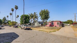Una calle residencial con casas, palmeras y vehículos estacionados.