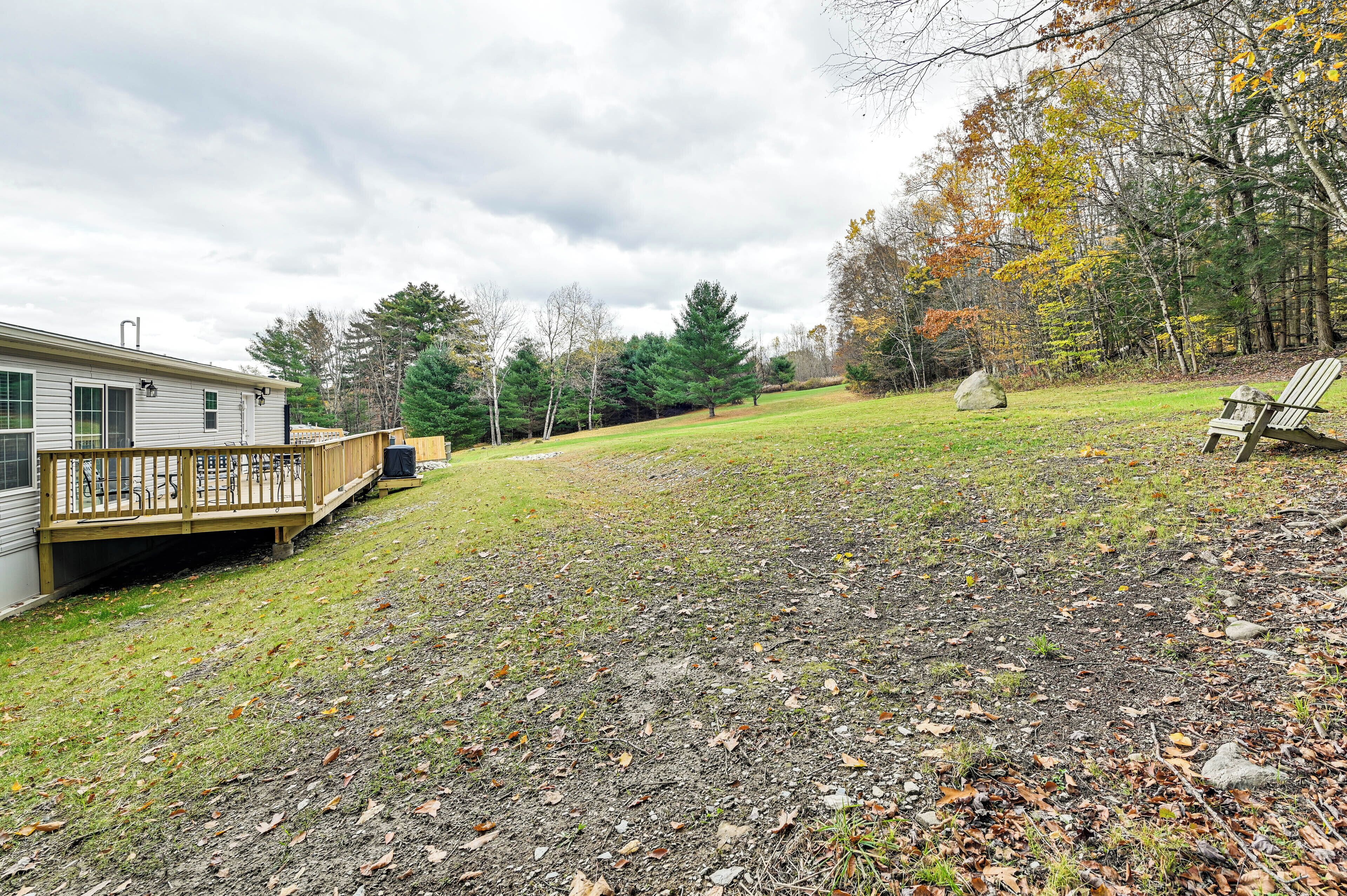 A residential property with a wooden deck, a grassy yard, and a large rock.