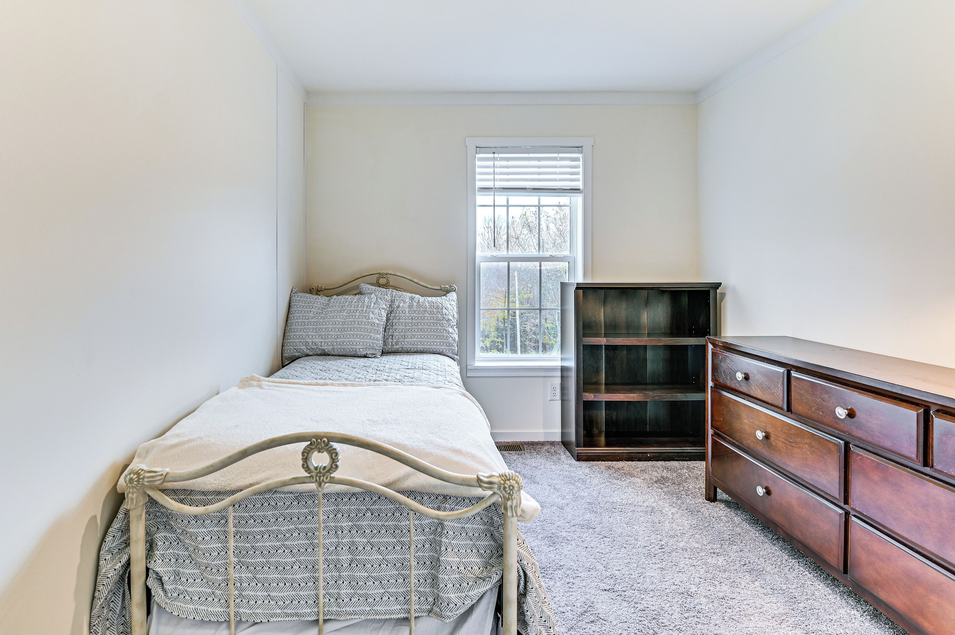 Une chambre à coucher avec un lit, une commode et une fenêtre.