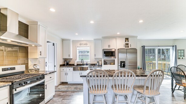 A modern kitchen with white cabinetry, stainless steel appliances, and a central island with bar stools. - 8 Mi to Jiminy Peak Resort: Mtn-view Home w/ Deck (Stephentown)
