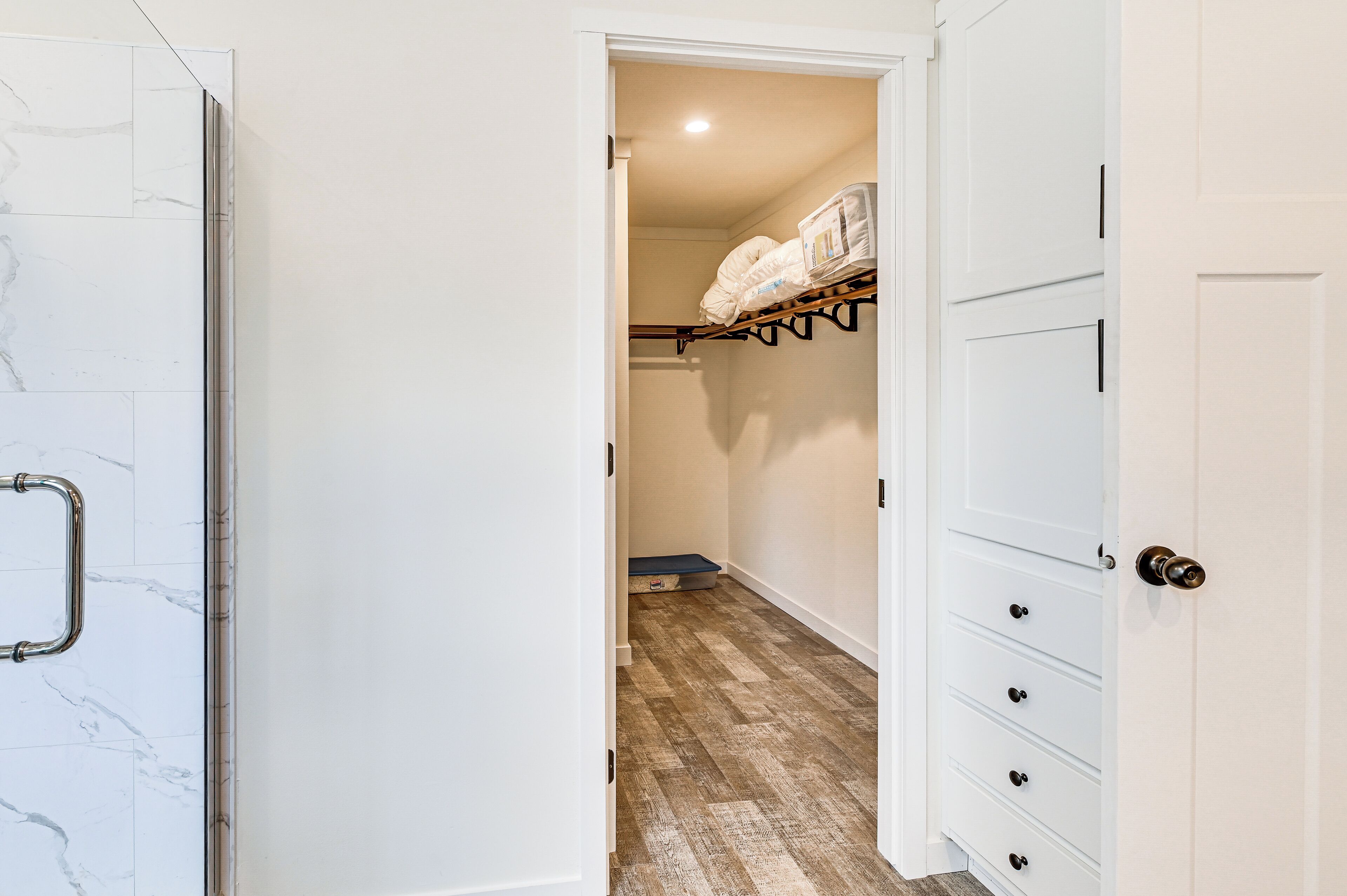 A hallway with a white door on the left, a wooden floor, and a white door on the right.