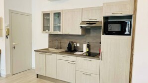 A compact kitchen with a microwave, sink, and cabinets. - Le Grand Cloutiers, Centre Ville, LR135 (La Rochelle)