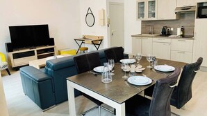 A modern living room with a TV, sofa, and dining table set for six. - Le Grand Cloutiers, Centre Ville, LR135 (La Rochelle)
