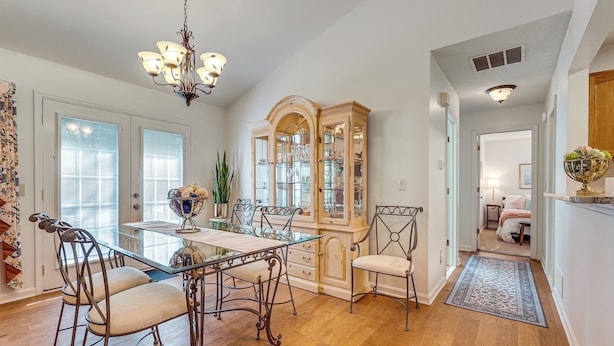 A dining area with a glass-top table, metal chairs, a chandelier, and a wooden cabinet with glass doors. - 2 Mi to Ksu: Family Home w/ Games, Near Parks (Kennesaw)