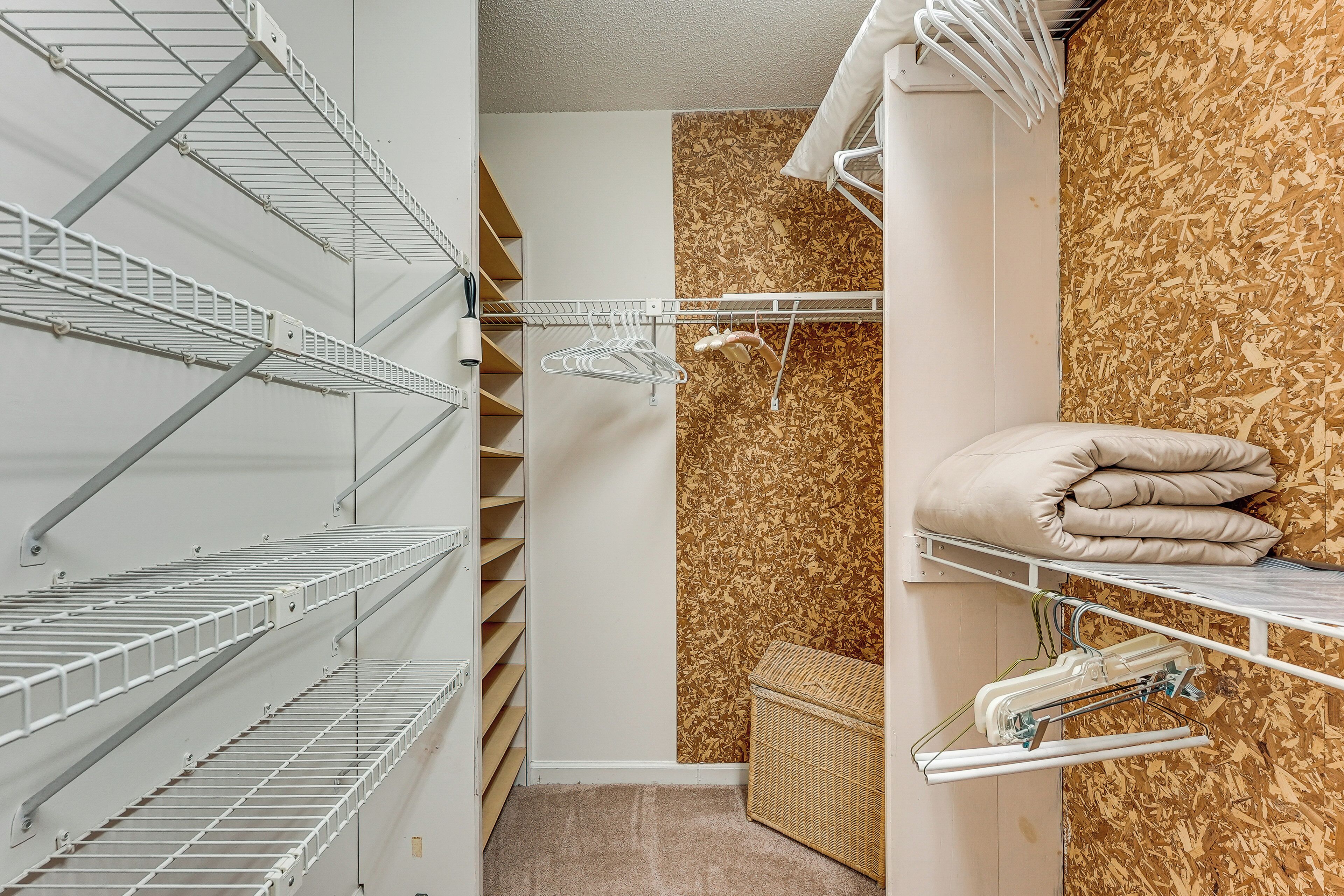 A storage closet with metal shelves, a wooden wall, and a wicker basket.
