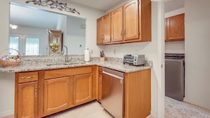 A kitchen with wooden cabinets, a granite countertop, a dishwasher, a toaster, and a refrigerator. - 2 Mi to Ksu: Family Home w/ Games, Near Parks (Kennesaw)