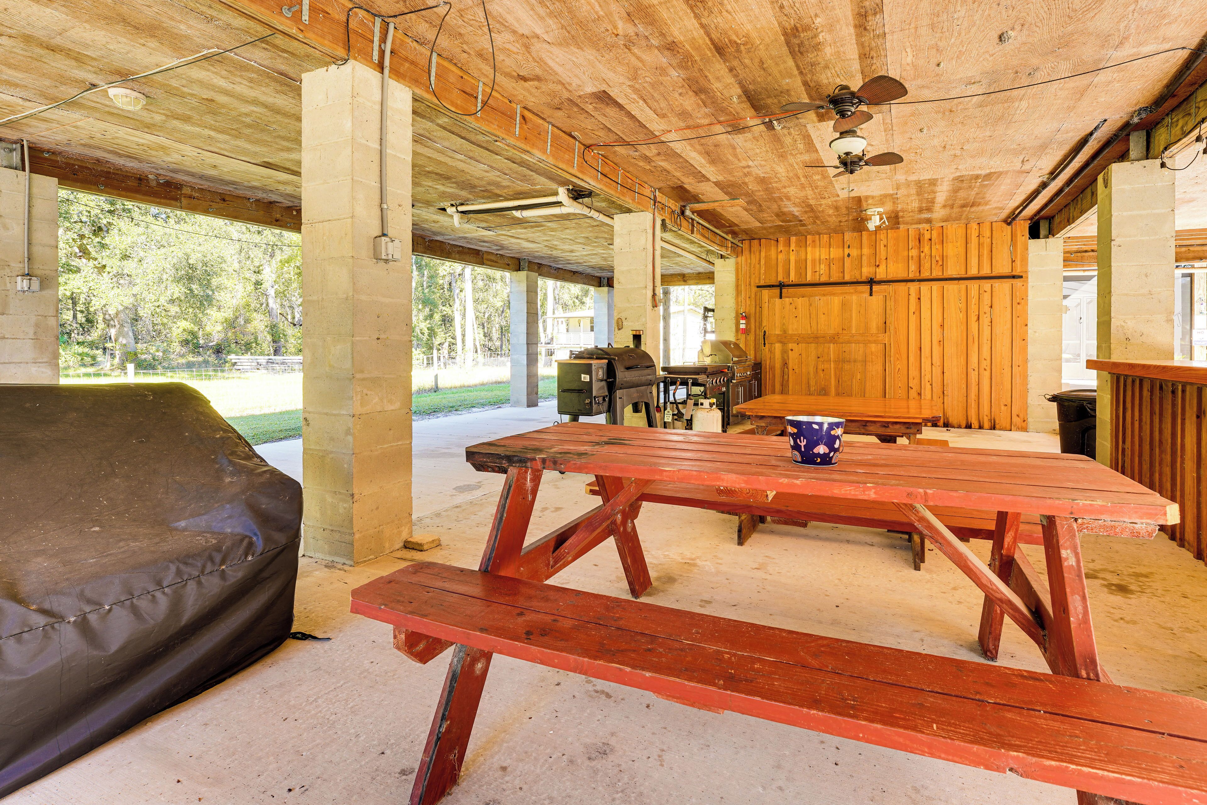 Un espace extérieur abrité avec des tables de pique-nique, un barbecue et un coin salon.