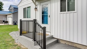 A house with a front porch, a black railing, and a small set of steps leading to the door. - Walk to Lagoon Saloon! Chic Home on Nugent's Canal (Port Clinton)