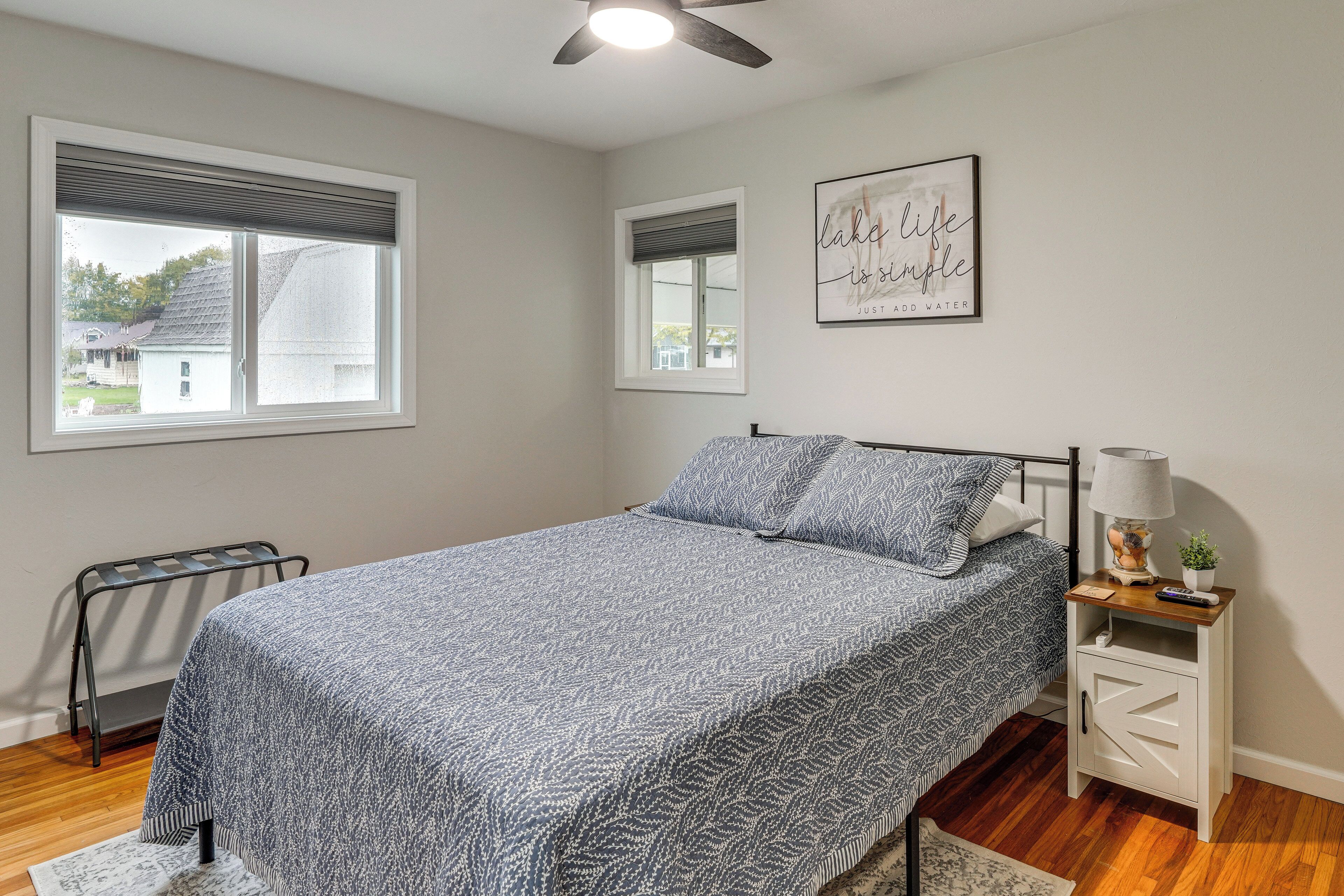 A bedroom with a bed, a nightstand, a ceiling fan, and a window with blinds.