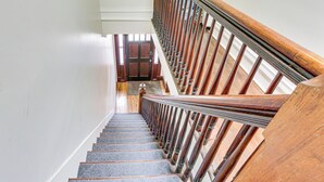 A wooden staircase with a handrail, leading to a landing with a door. - Explore & Work! Stylish Washington Heights Duplex (Newburgh)