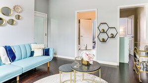 A modern living room with a light blue sofa, a round coffee table, and decorative mirrors on the wall. - Explore & Work! Stylish Washington Heights Duplex (Newburgh)