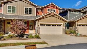 A two-story house with a garage, a front porch with a potted plant, and a small garden area.