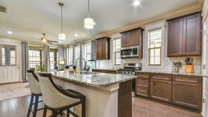 A spacious kitchen with dark wooden cabinets, a granite countertop, and a central island with bar stools.